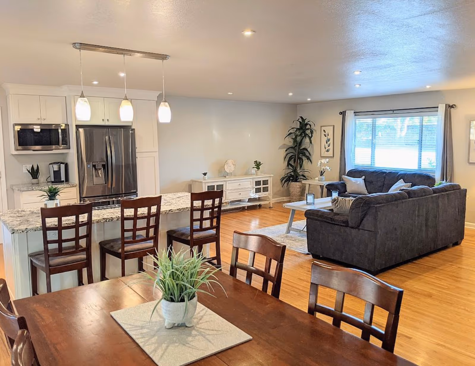 Bright open-concept kitchen and living area with island, dining table, and sofa.