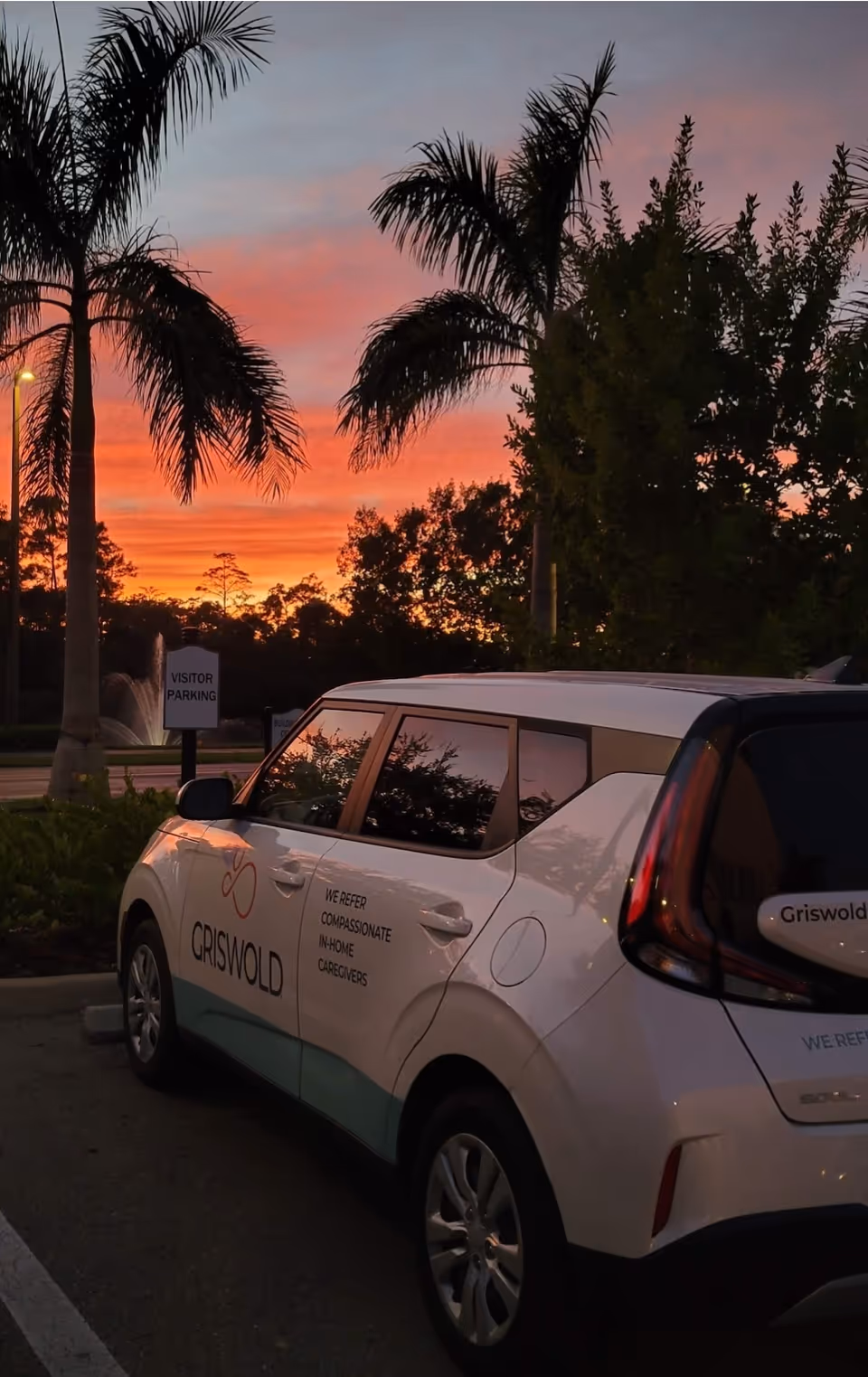 Sunset scene in a parking lot with a Griswold care vehicle beside palm trees.