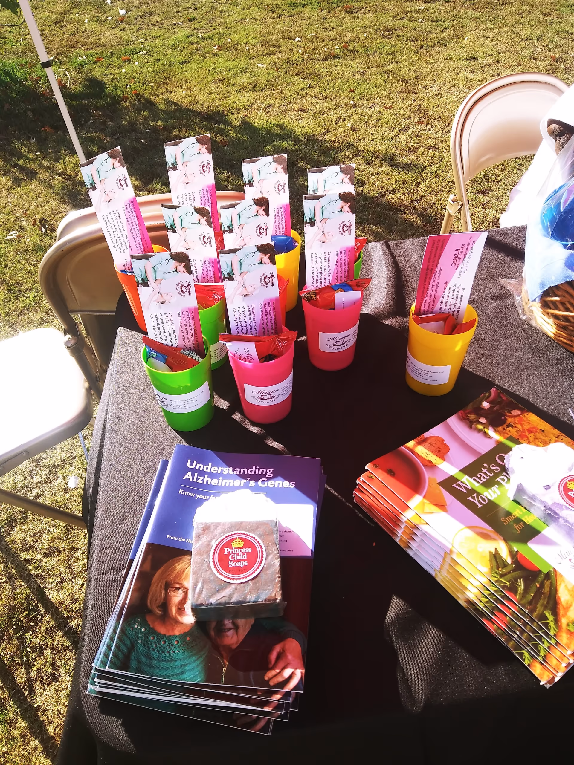 Outdoor table with brochures, pamphlets, and colorful cups at an awareness event.