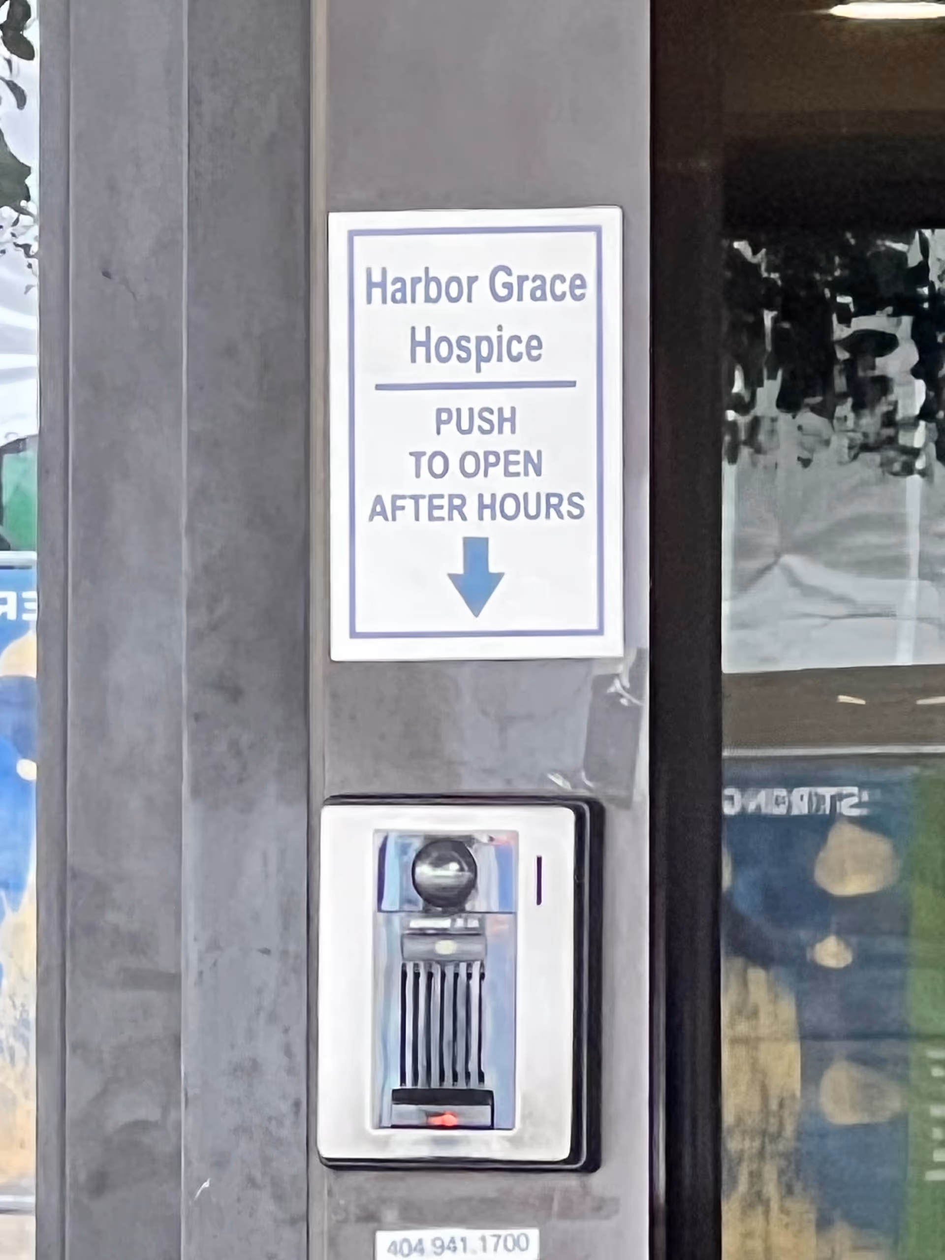 Exterior wall with Harbor Grace Hospice sign and door access panel.