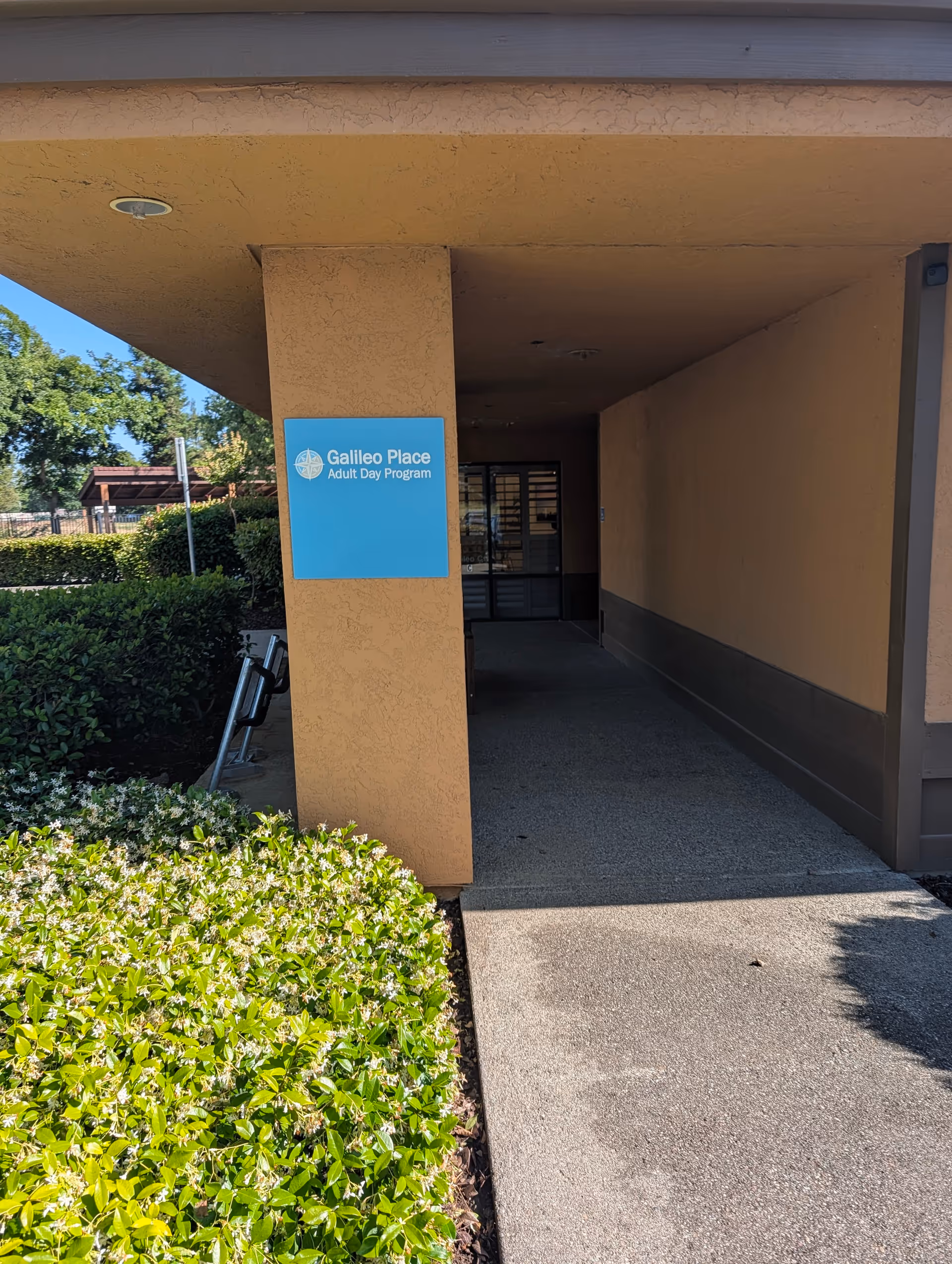 Exterior entrance to Galileo Place Adult Day Program with a blue sign on a column.