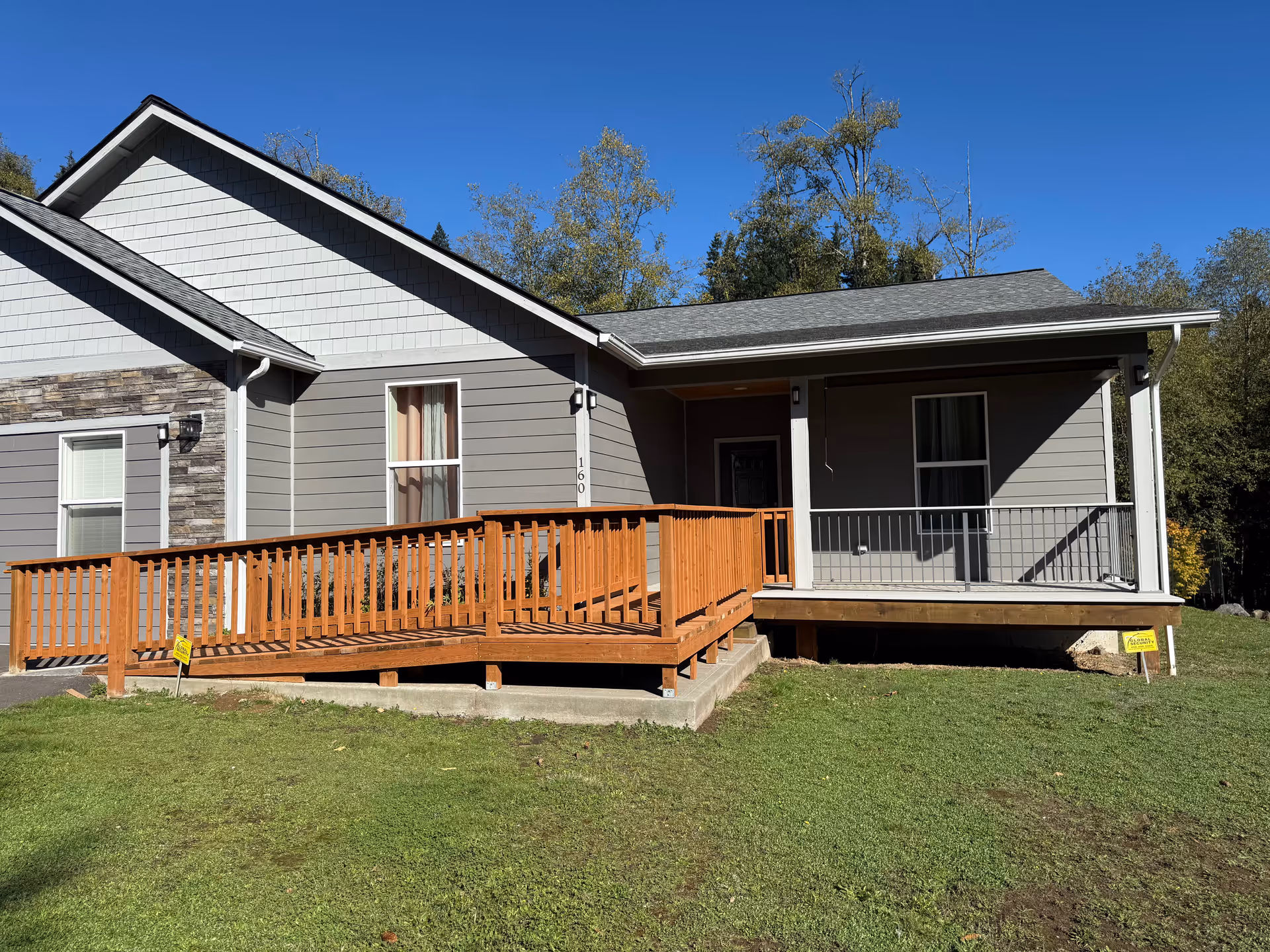 Exterior view of a modern single-story building with a wooden ramp leading to a porch.