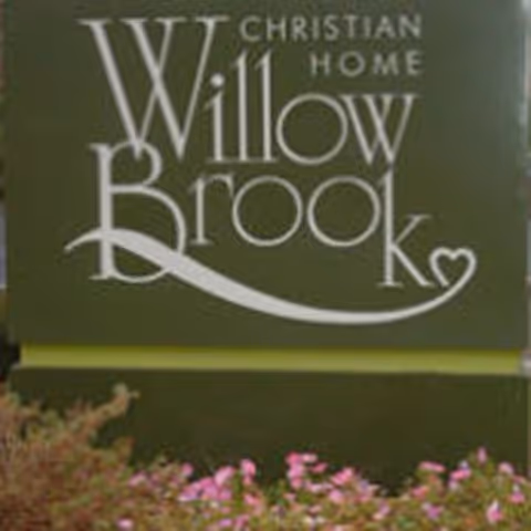 Willow Brook Christian Home sign on a green exterior wall with flowers.