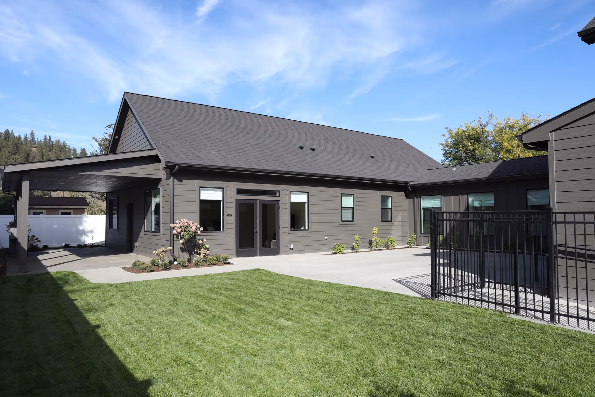 Modern gray, single-story senior living facility with a covered entrance and lawn.
