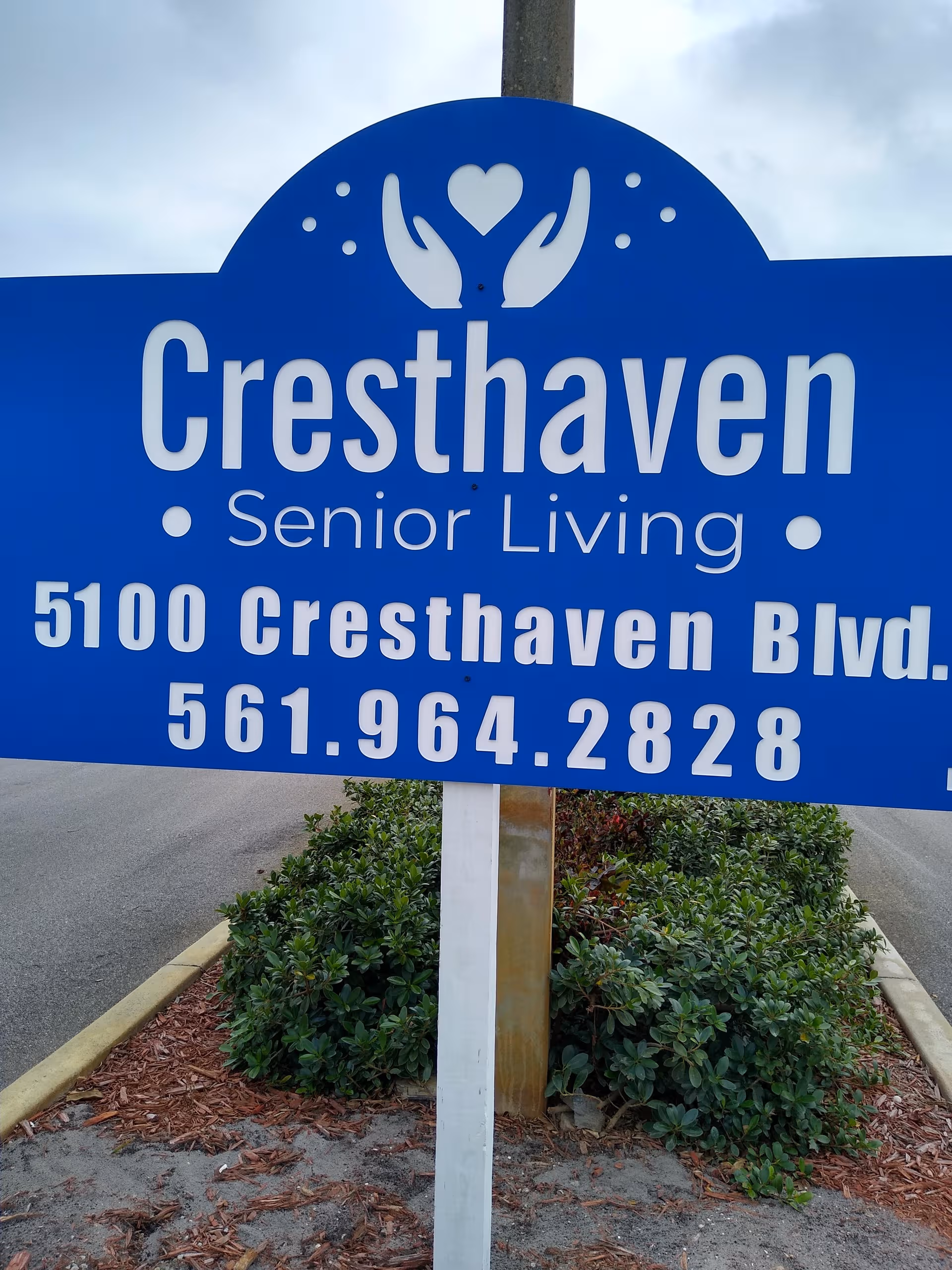 A large blue Cresthaven Senior Living sign with address and phone number.