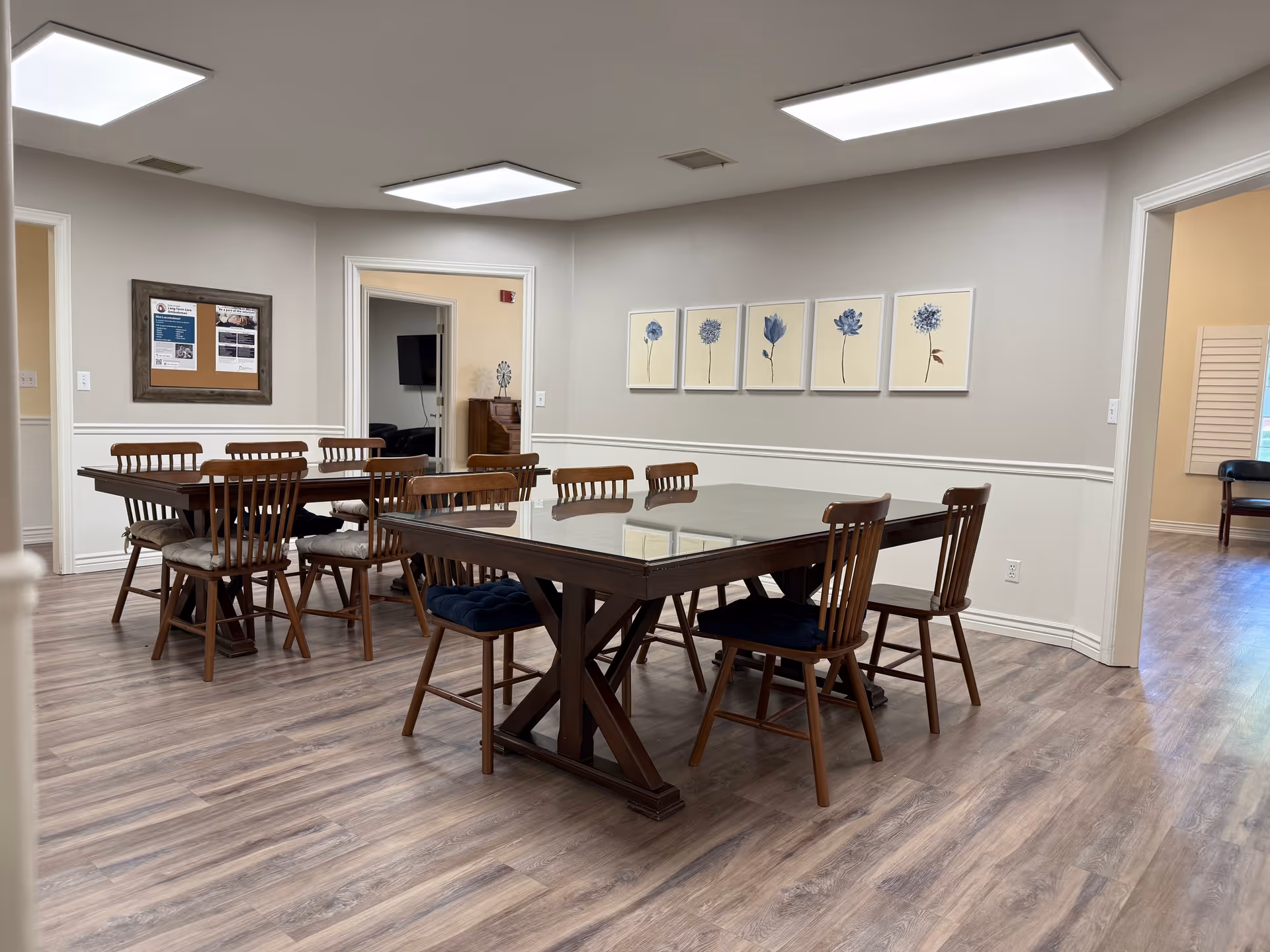 A spacious dining room with wooden tables and chairs in a senior living facility.