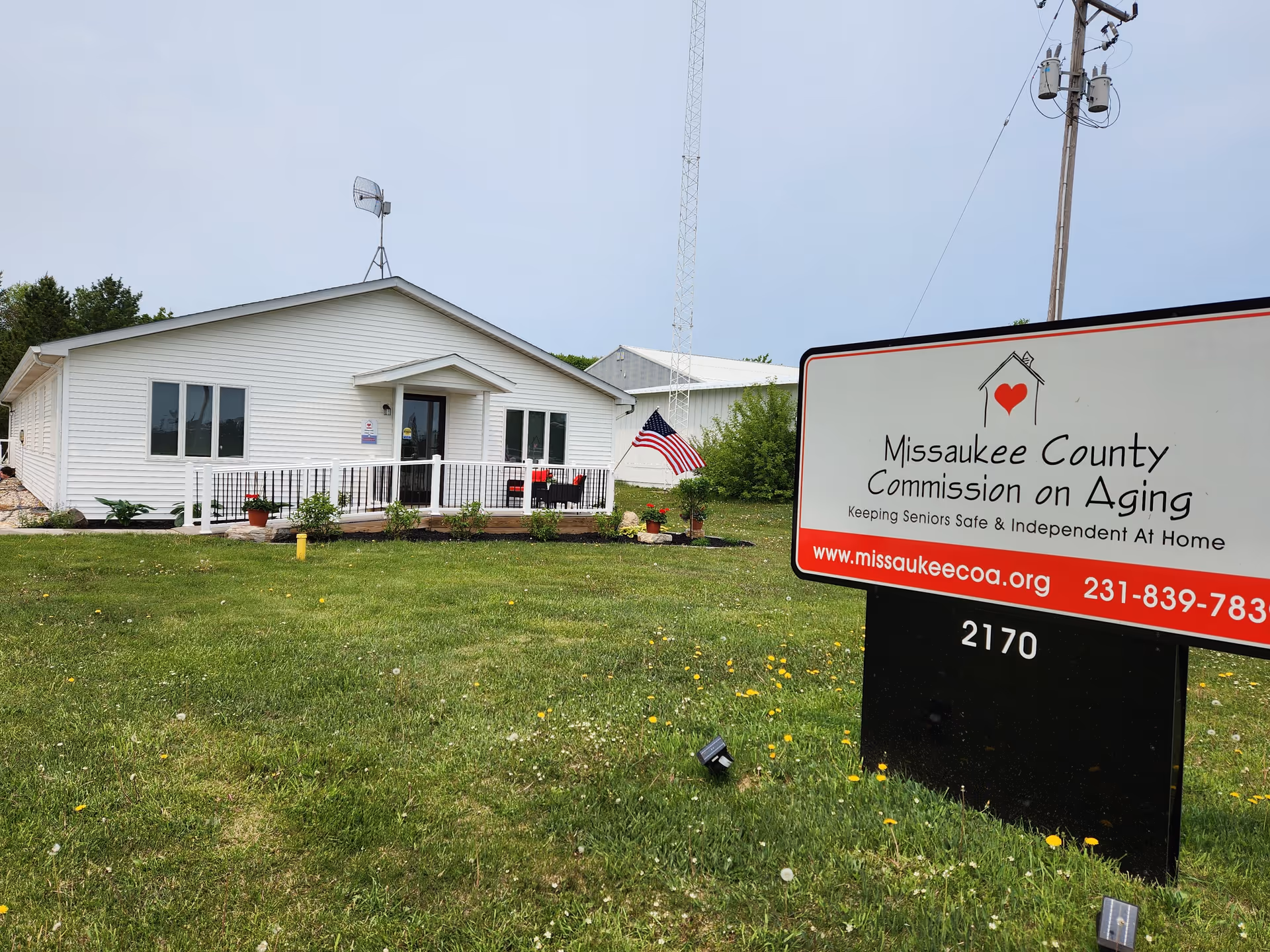 Single-story white building with a porch and Missaukee County Commission on Aging sign on lawn.