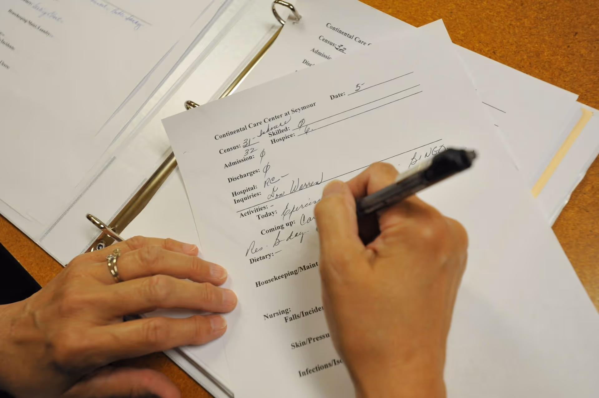 Close-up of a hand signing a form labeled Continental Care Center on a desk.