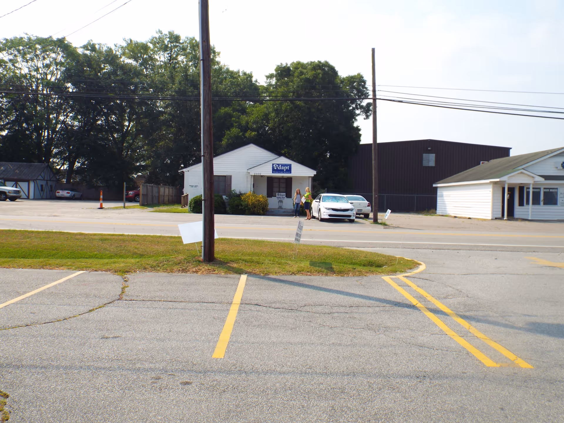 Street view of a building with Adapt Home Care sign and two people near a car.