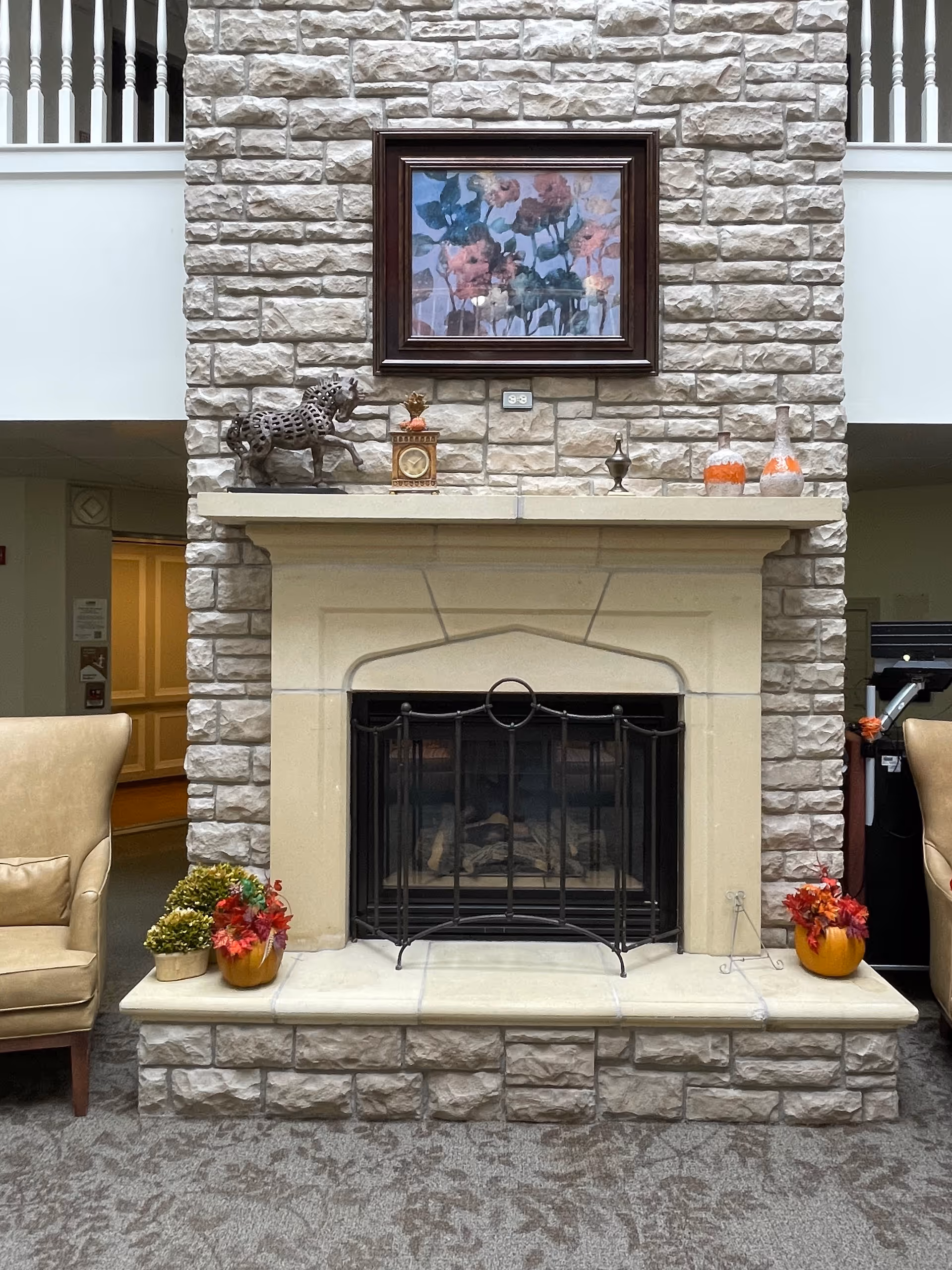 Stone fireplace with framed painting and mantle decor in a cozy lobby seating area.