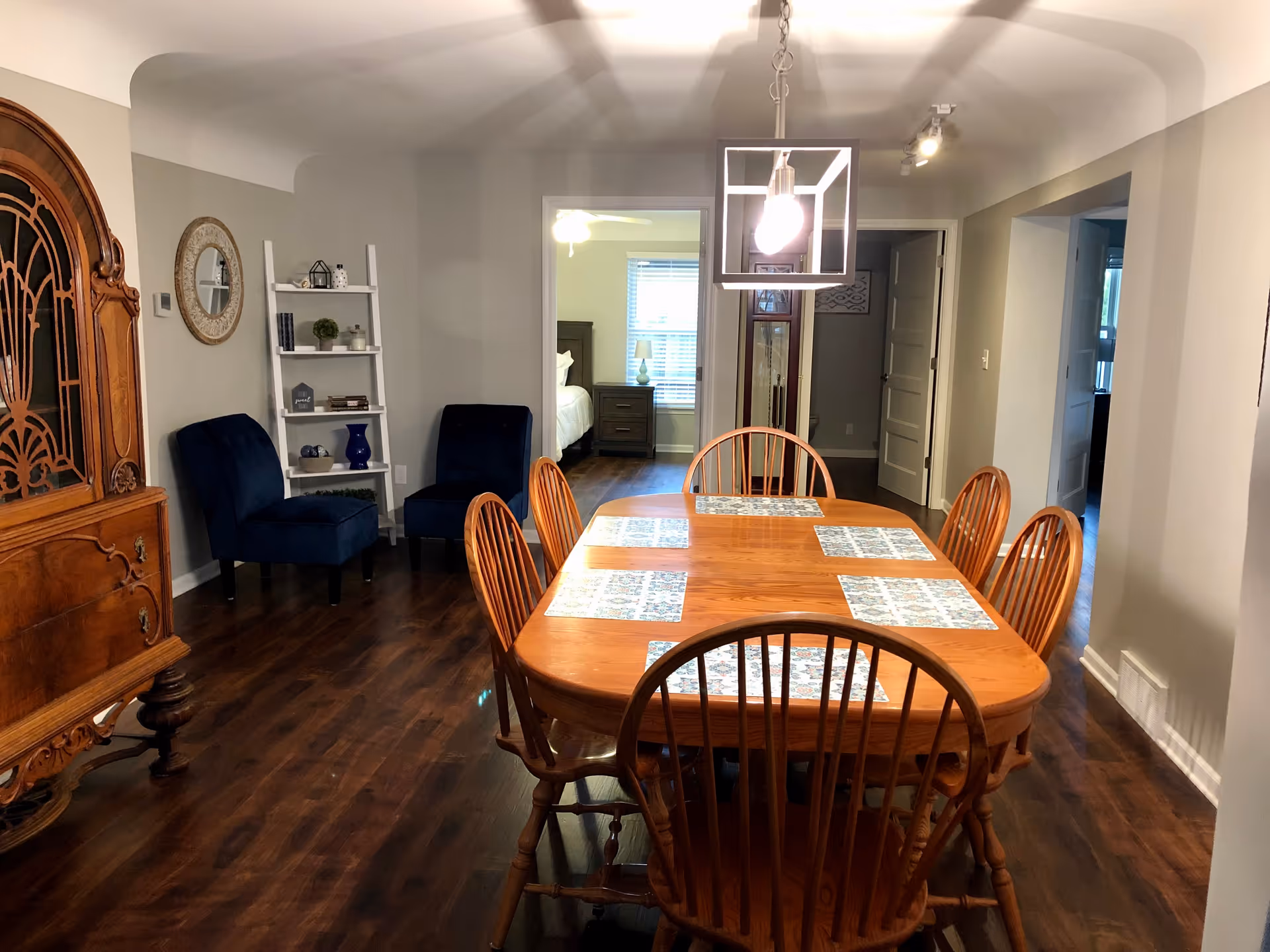 Wood dining table with multiple chairs in a well-lit communal dining room.