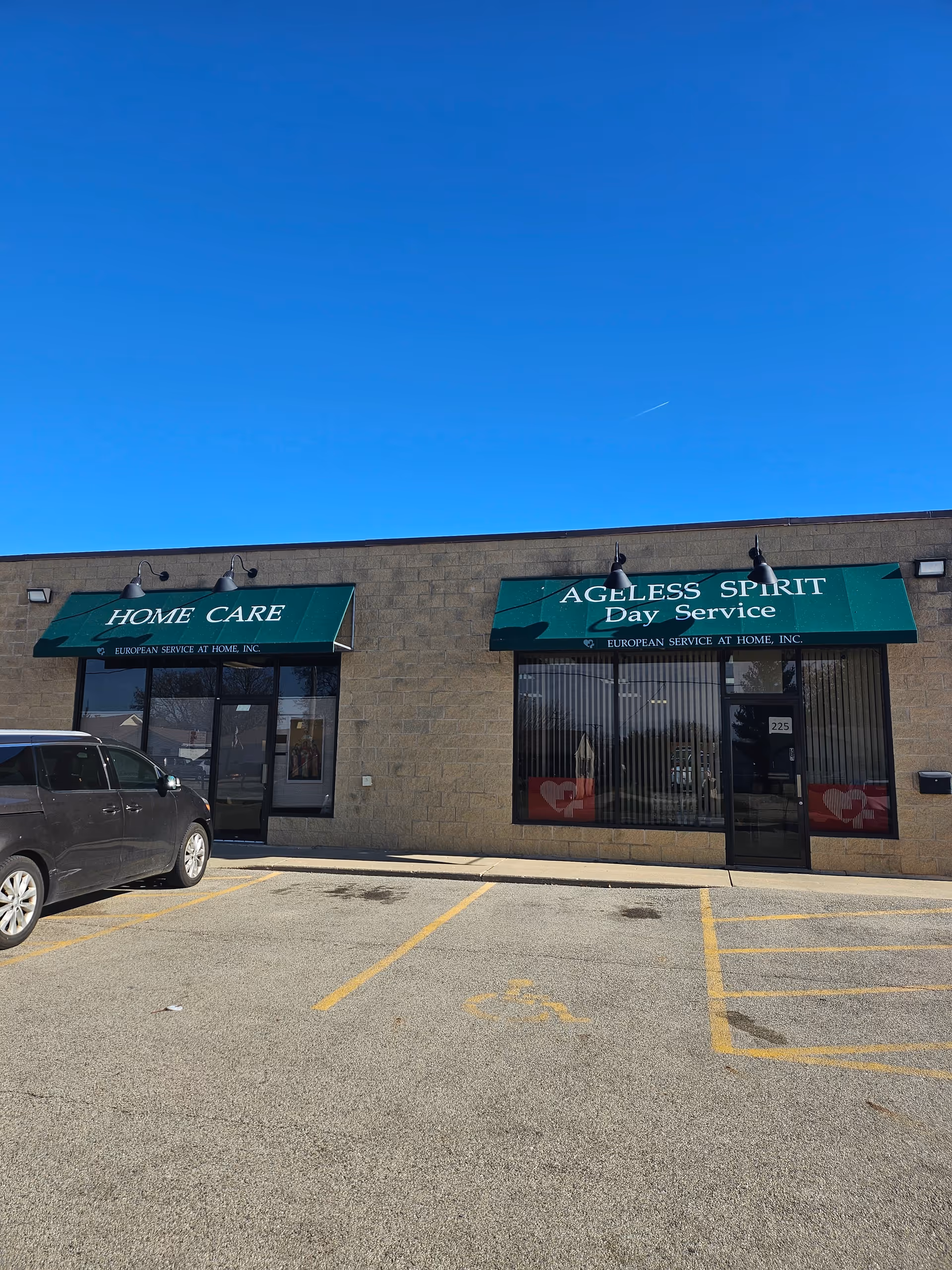 Exterior view of European Service at Home storefronts with green awnings and a parked car.