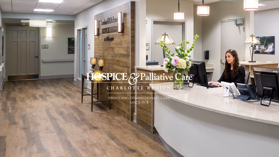 Reception area of hospice and palliative care center with curved desk and staff at computers.