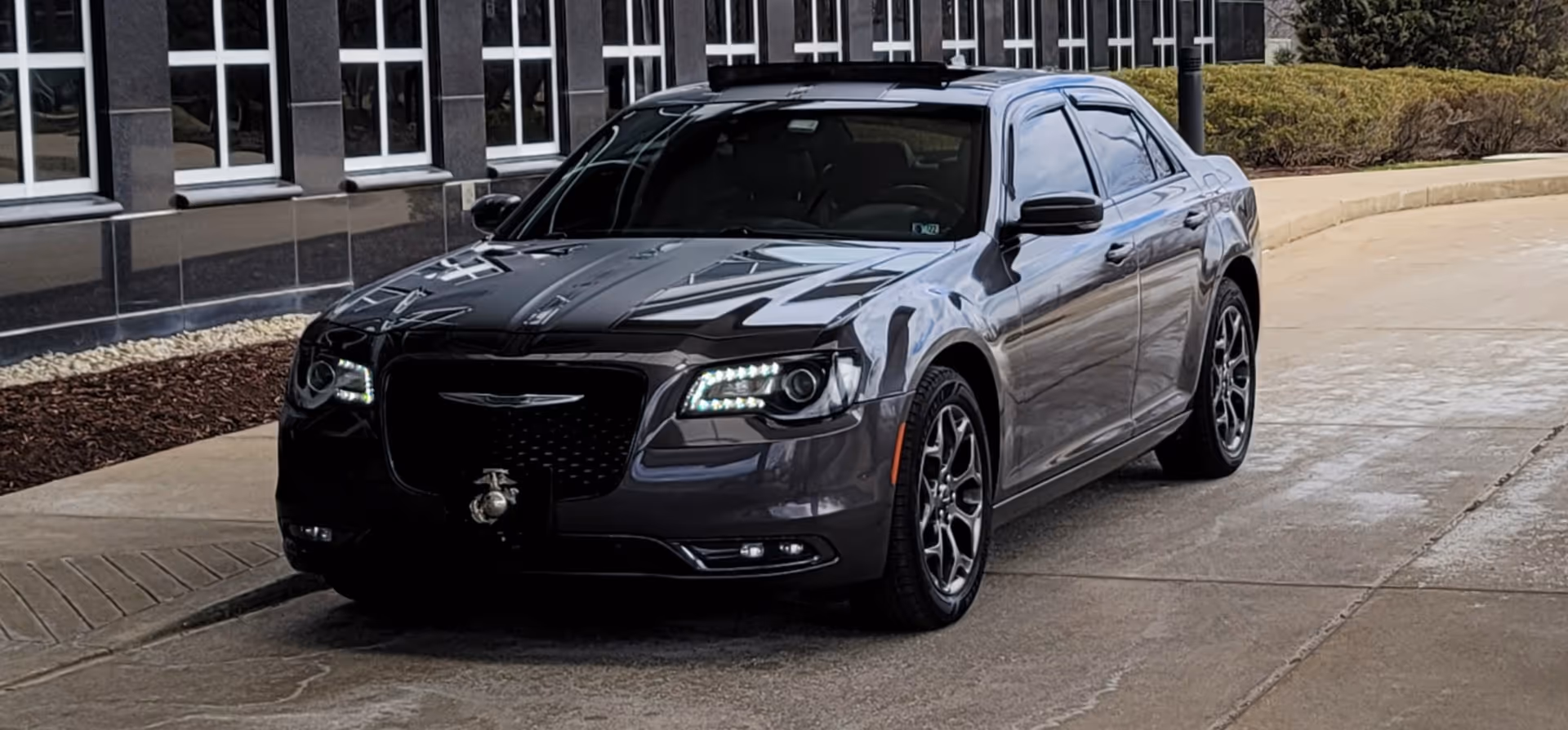 Exterior shot of a gray sedan in front of a modern building.