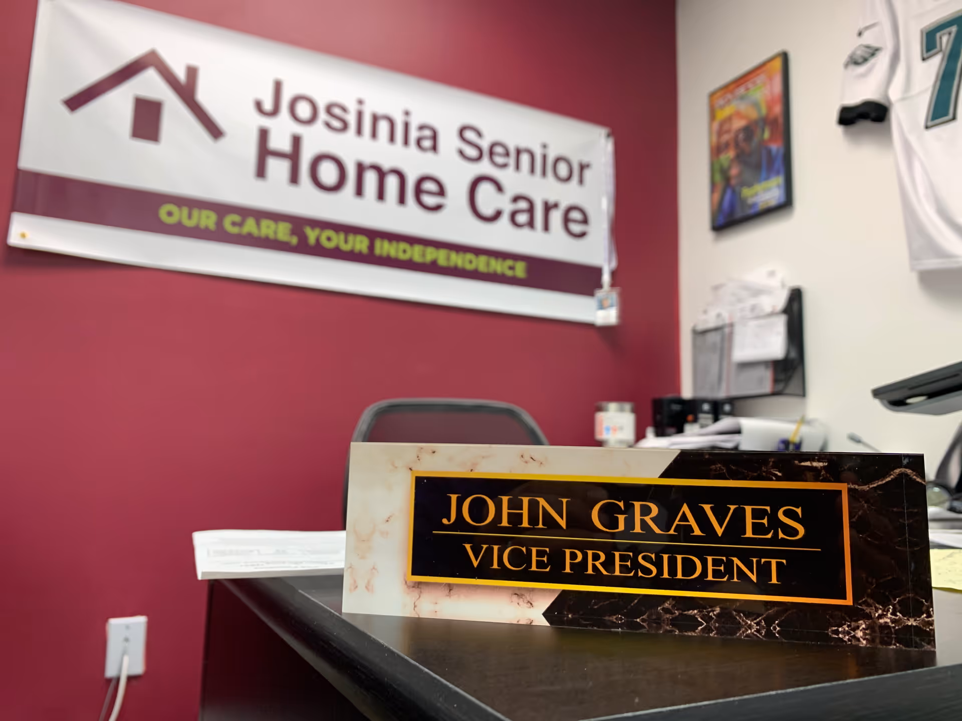 Reception desk area with Josinia Senior Home Care banner and nameplate plaque