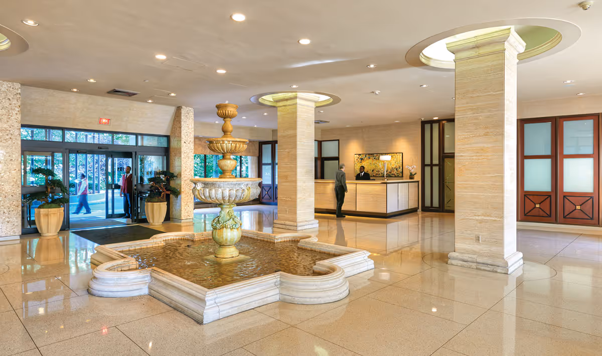 Spacious interior lobby featuring a central fountain, pillars, and a reception desk.