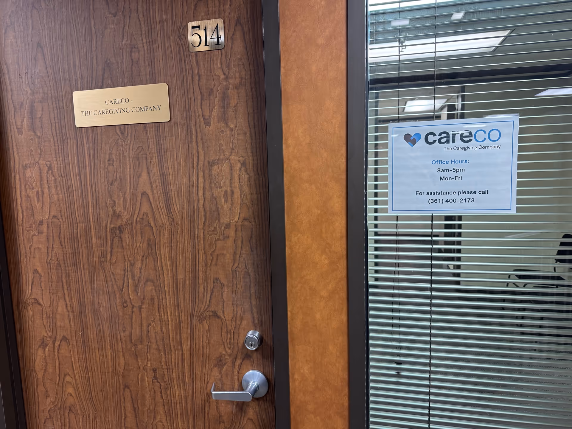 Wooden door labeled 514 beside glass window displaying CareCo sign and office hours.