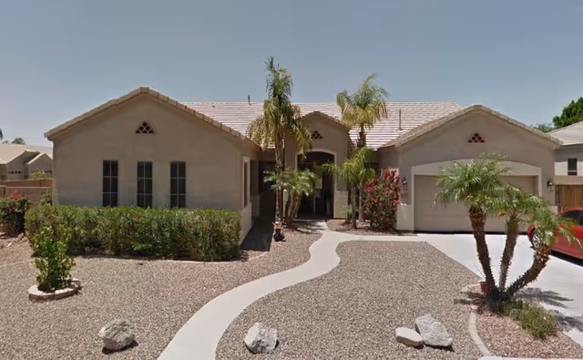 Front exterior of Mountain Vista Manor Corp Assisted Living, a single-story beige building with palm trees.