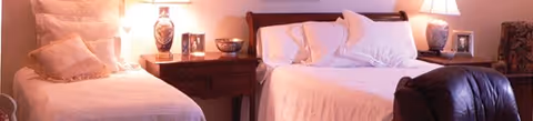 A cozy bedroom with two twin beds, nightstands, and lamps in soft lighting.