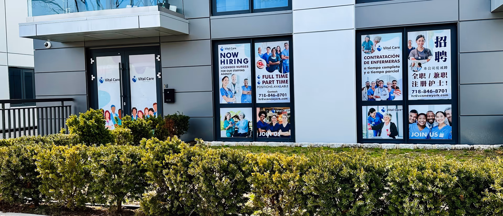 Exterior view of Vital Care Solutions facility with large recruitment posters in windows.