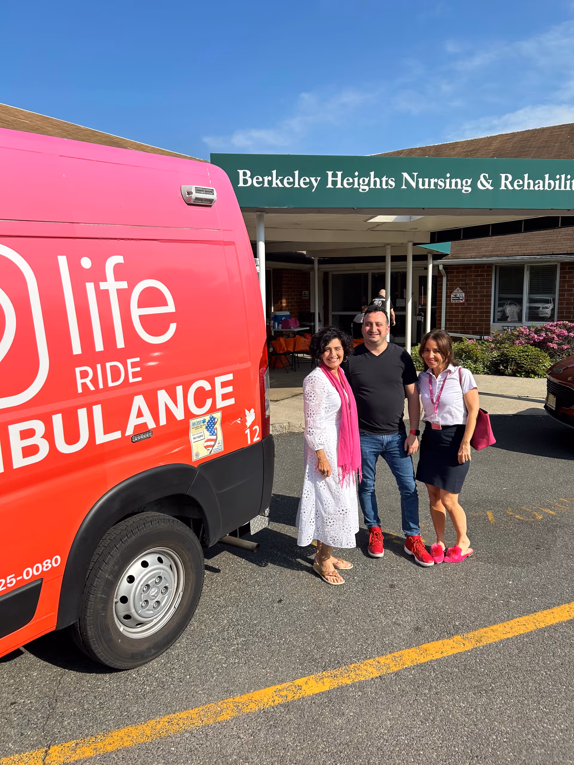 Three people stand beside a pink Life Ambulance in front of Berkeley Heights Nursing & Rehabilitation.