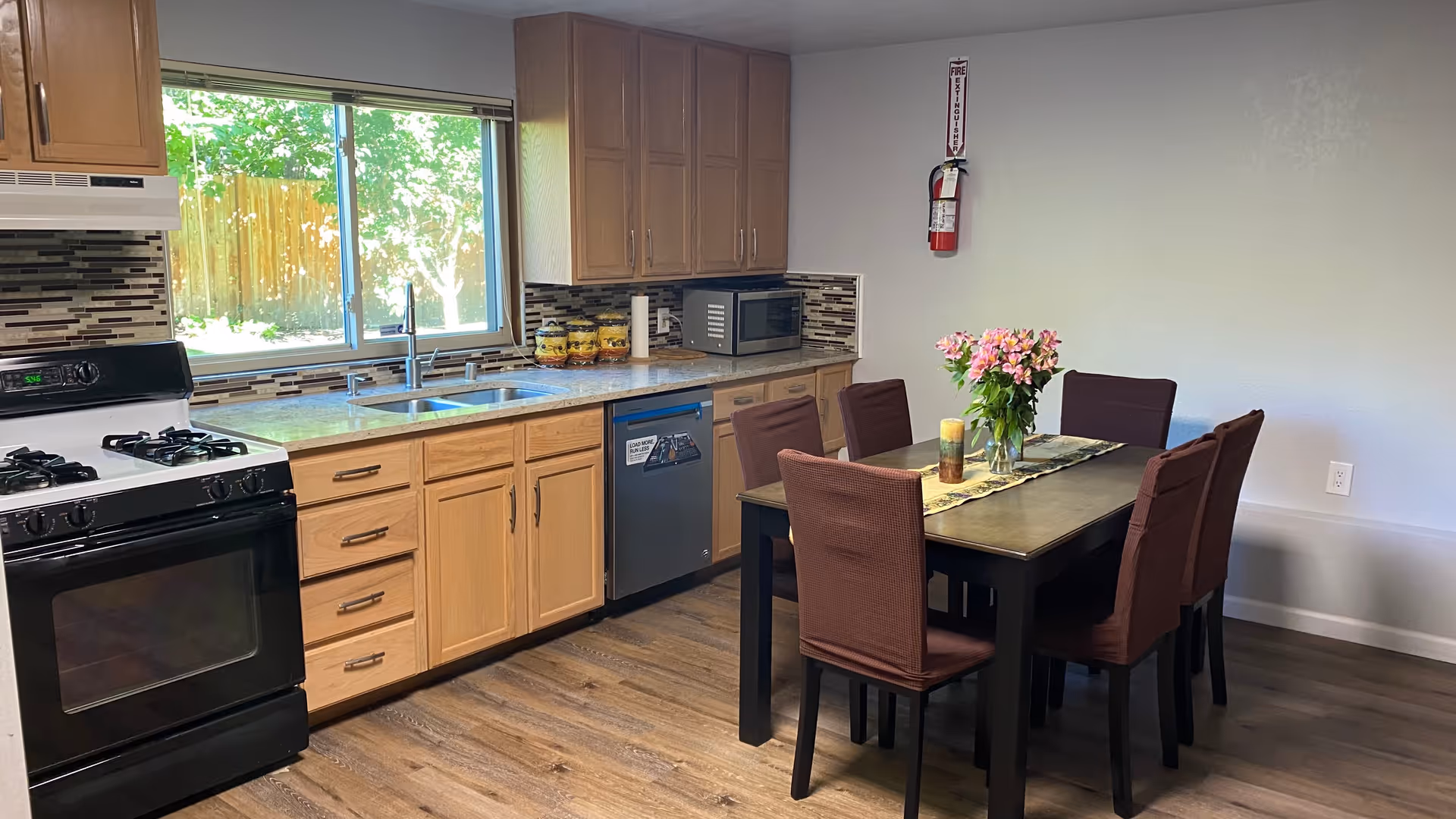Bright kitchen-dining area with wooden cabinets, stainless appliances, and a dining table.