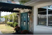 Front exterior view of Manatee River Assisted Living with a teal entry door and stone facade.