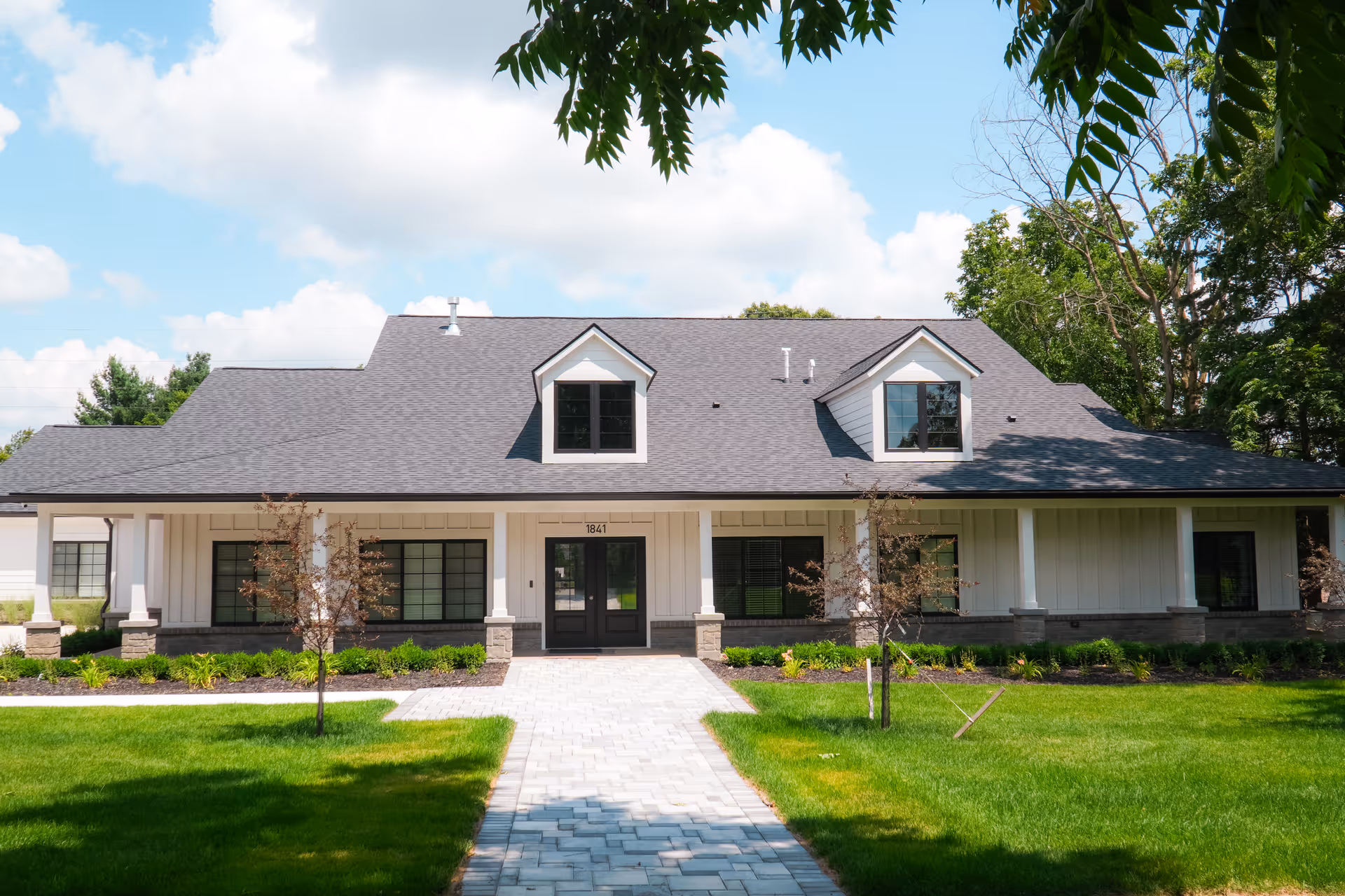 Front exterior of a single-story senior living facility with a paved walkway and lawn.