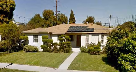 Single-story white care facility front with trimmed shrubs and a central walkway.