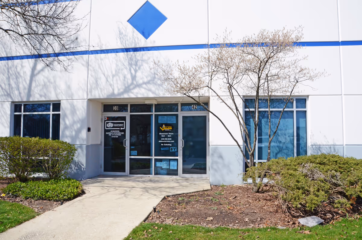 Front view of a white commercial building with glass doors and leafless trees.