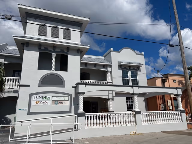 Exterior view of a light gray, multi-story building with arches and columns.