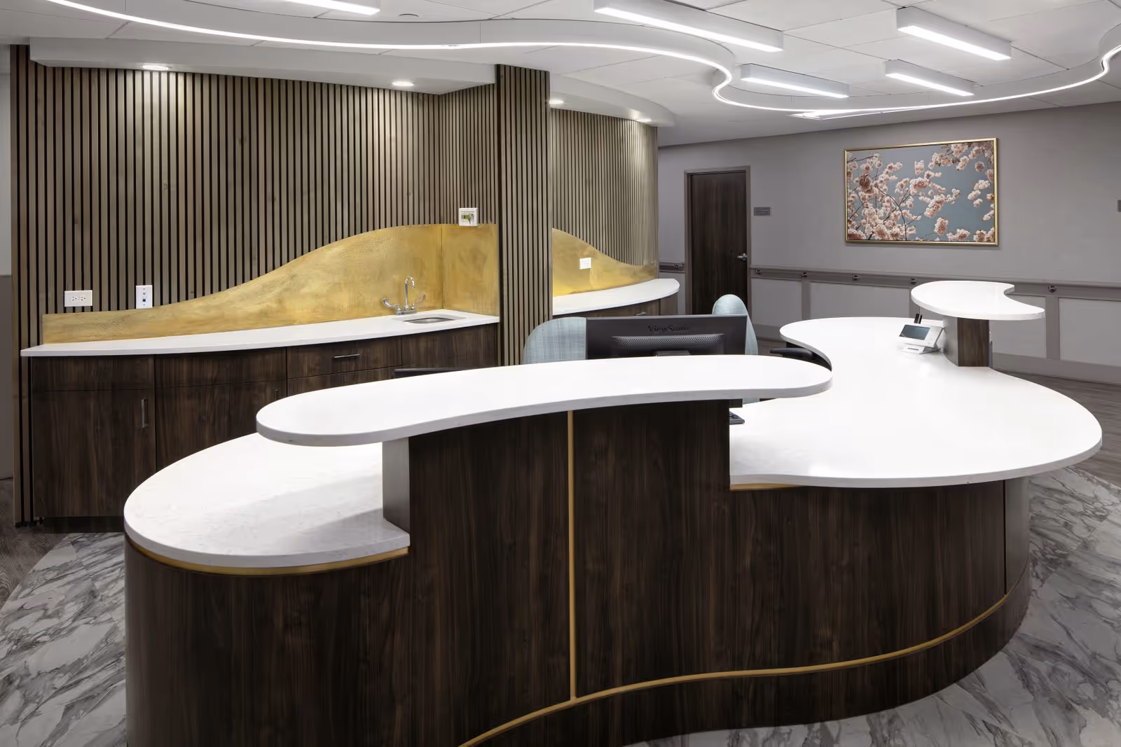 Curved white reception desk with dark wood base in a modern facility lobby.