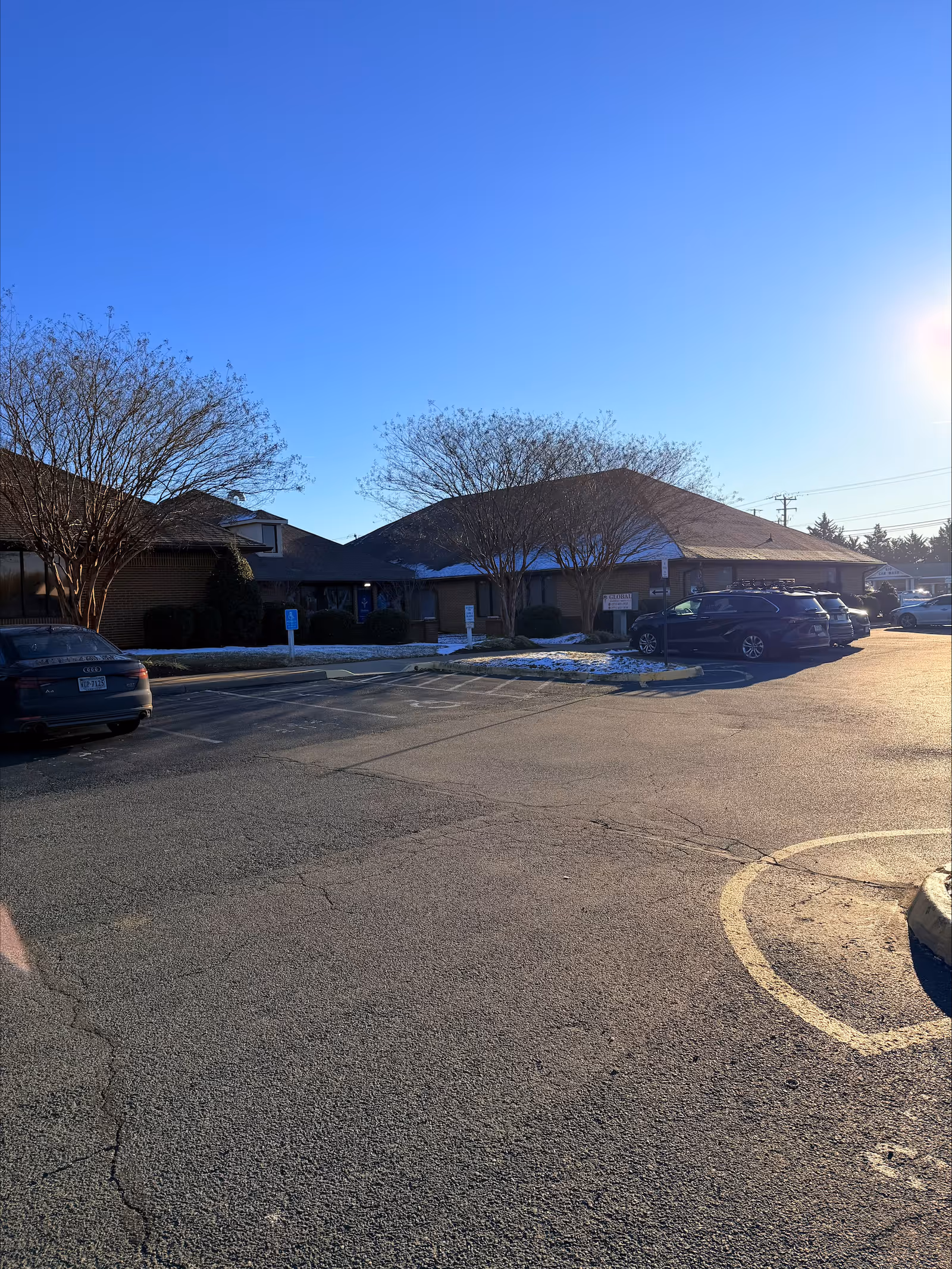Single-story facility exterior with a front parking lot and leafless trees.