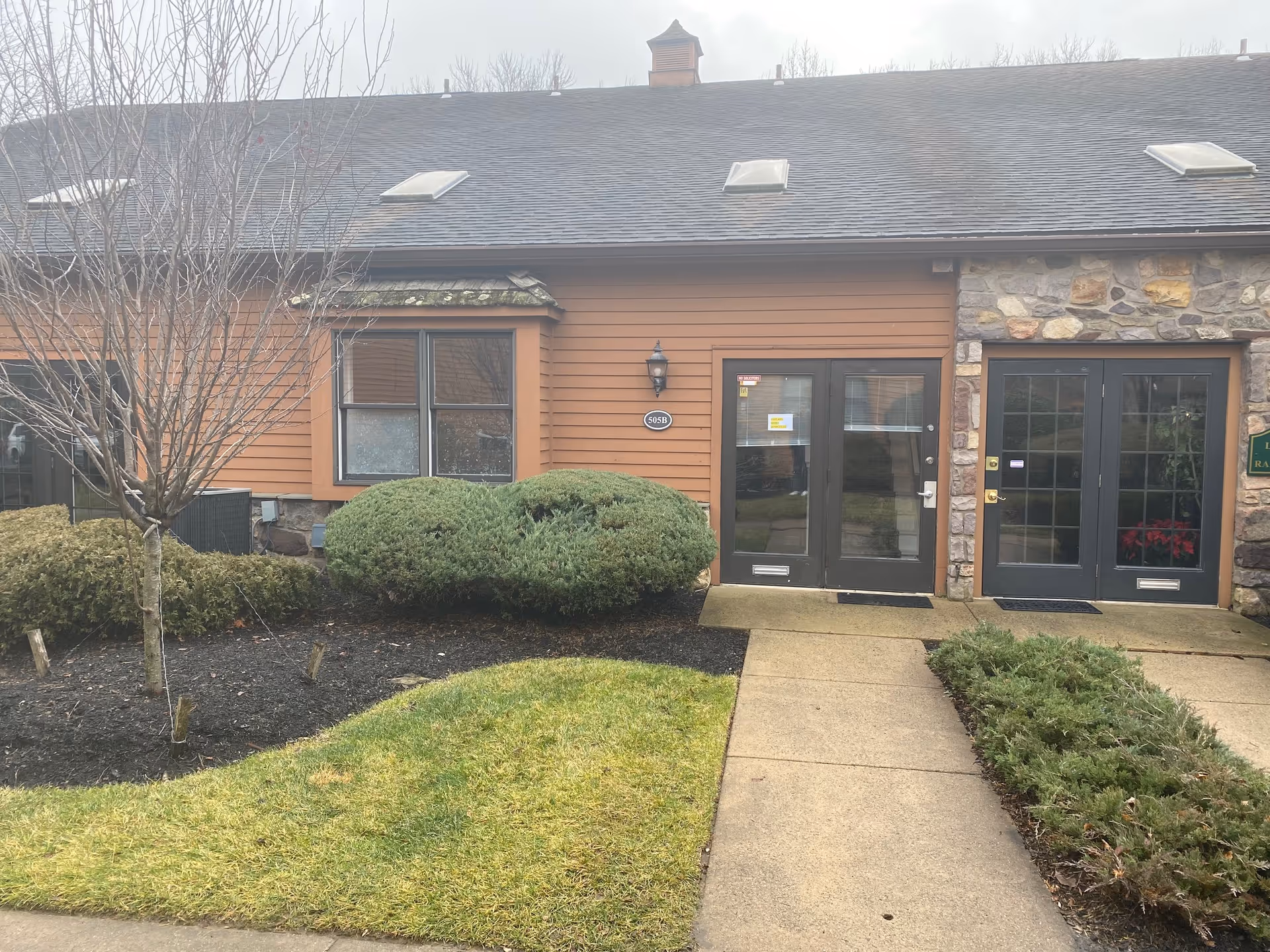 Front entrance of a senior living facility with double doors and stone facade.