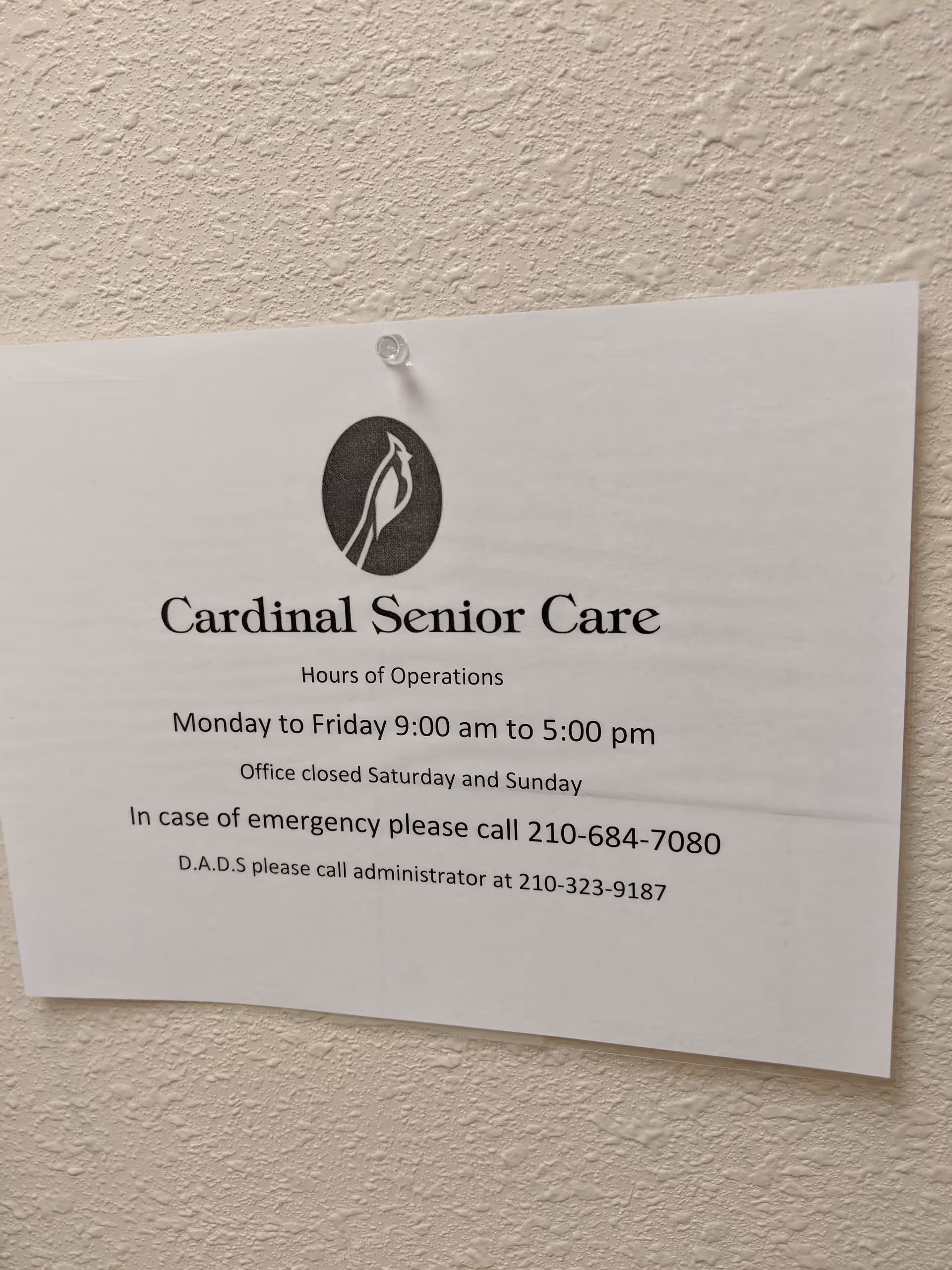 Cardinal Senior Care sign with hours taped to a textured interior wall.