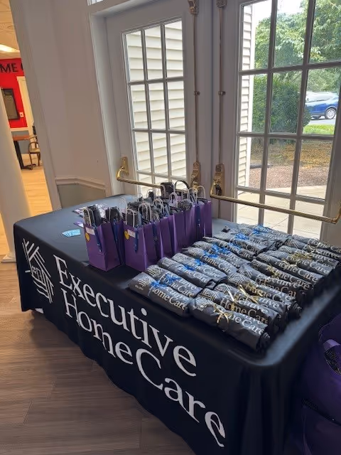 Table with branded water bottles and purple gift bags near glass doors inside.