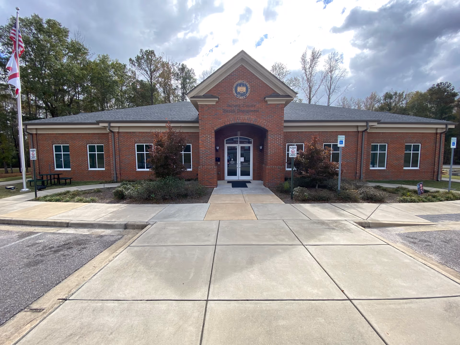 Exterior brick building with central arched entrance and landscaped surroundings.
