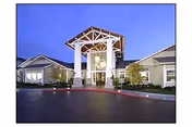 Front entrance of Oak View Senior Apartments featuring a white arch and landscaped surroundings.