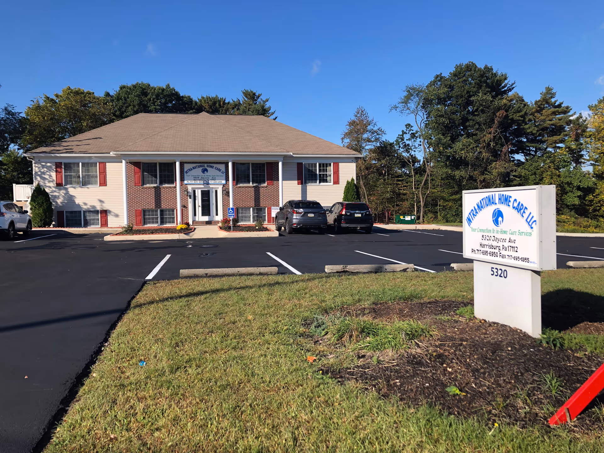 Exterior view of a two-story care facility with a sign and parking.