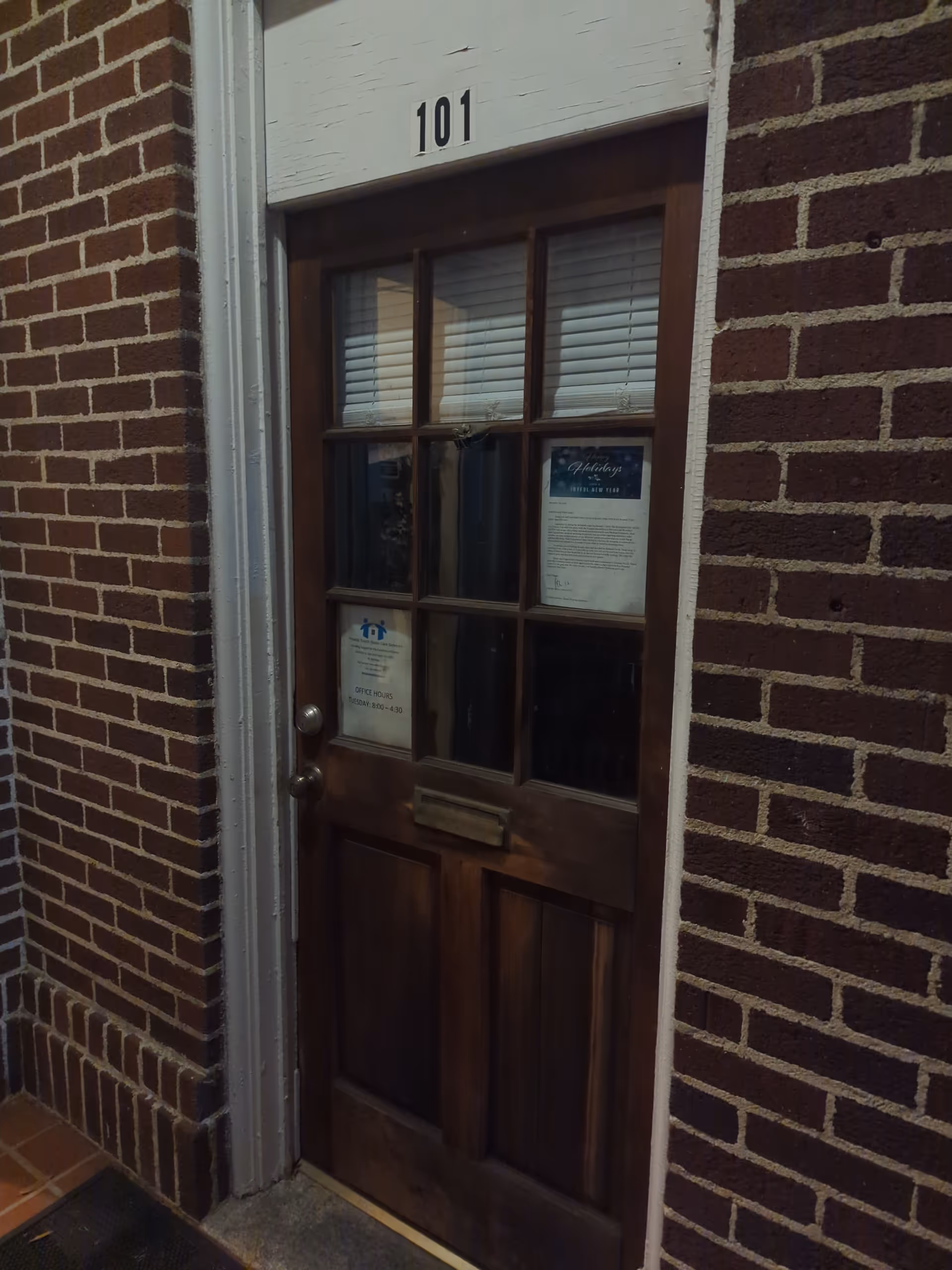 Brick exterior wall with a wooden door labeled 101 and a mail slot.
