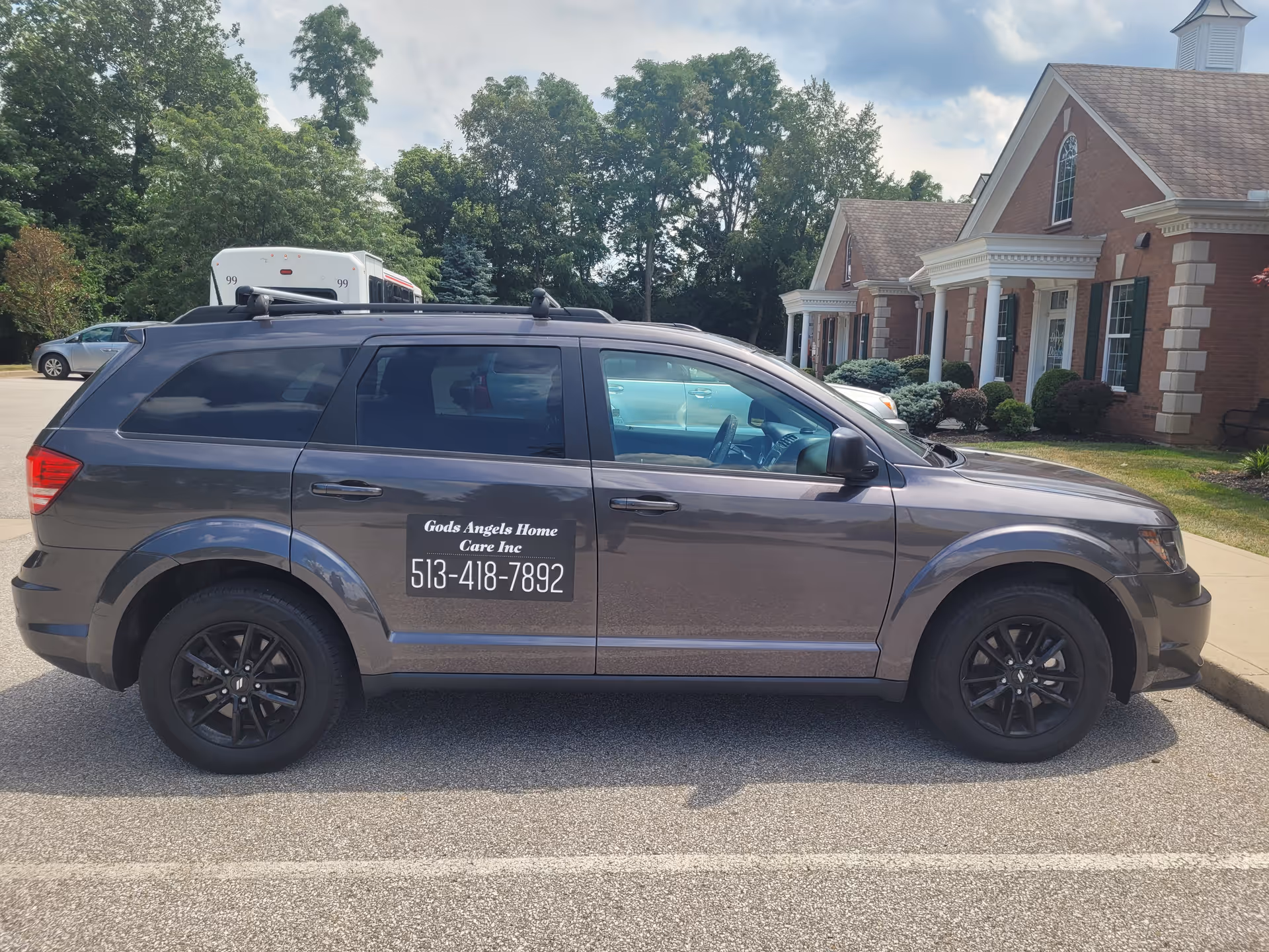 Gray SUV with a care company logo parked in front of a brick senior facility.