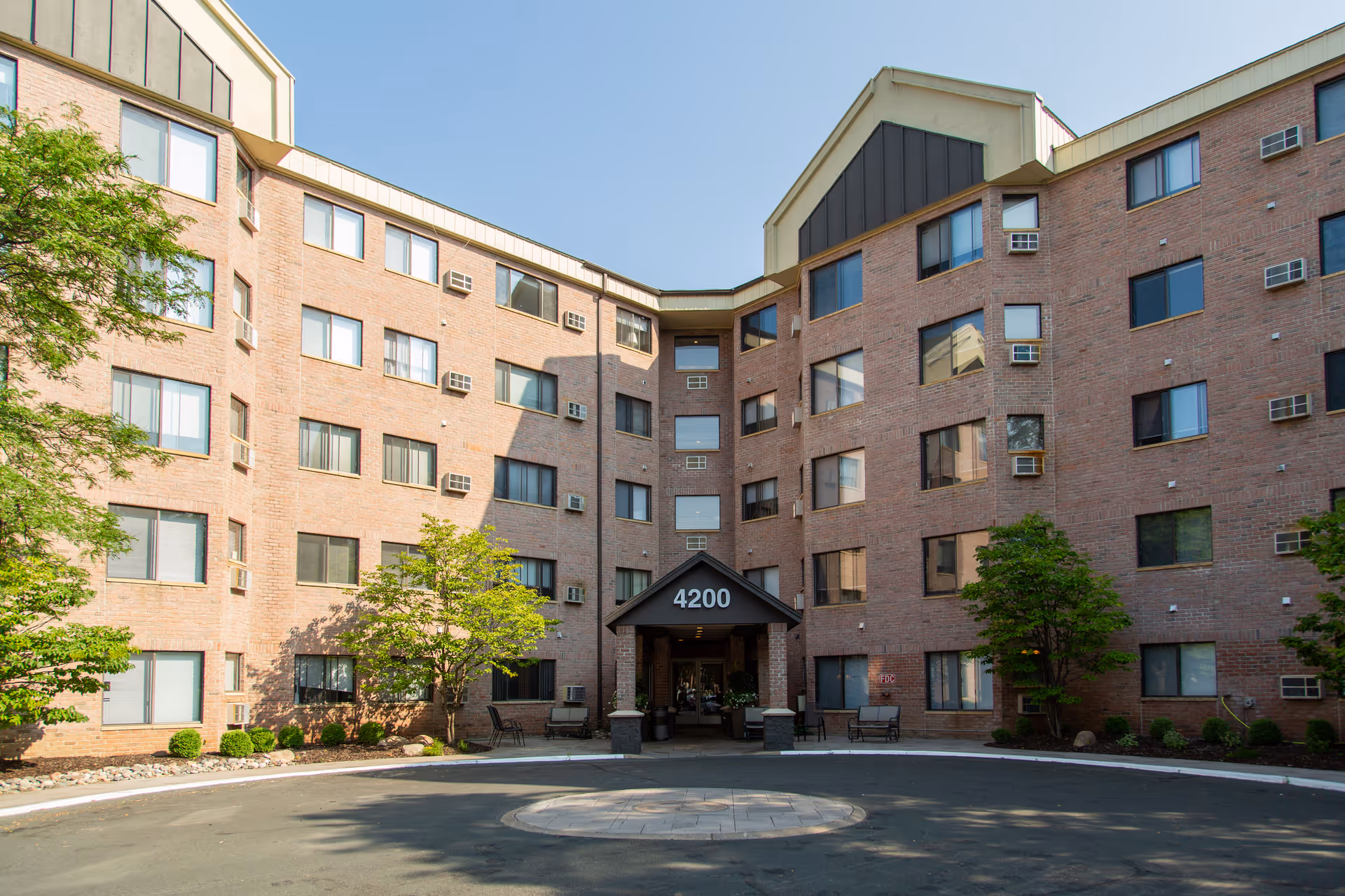 Brick senior living building exterior with a central entrance and landscaping