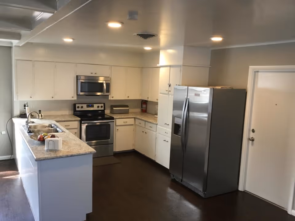 Modern white kitchen with stainless steel appliances inside Merrill Senior Services facility.