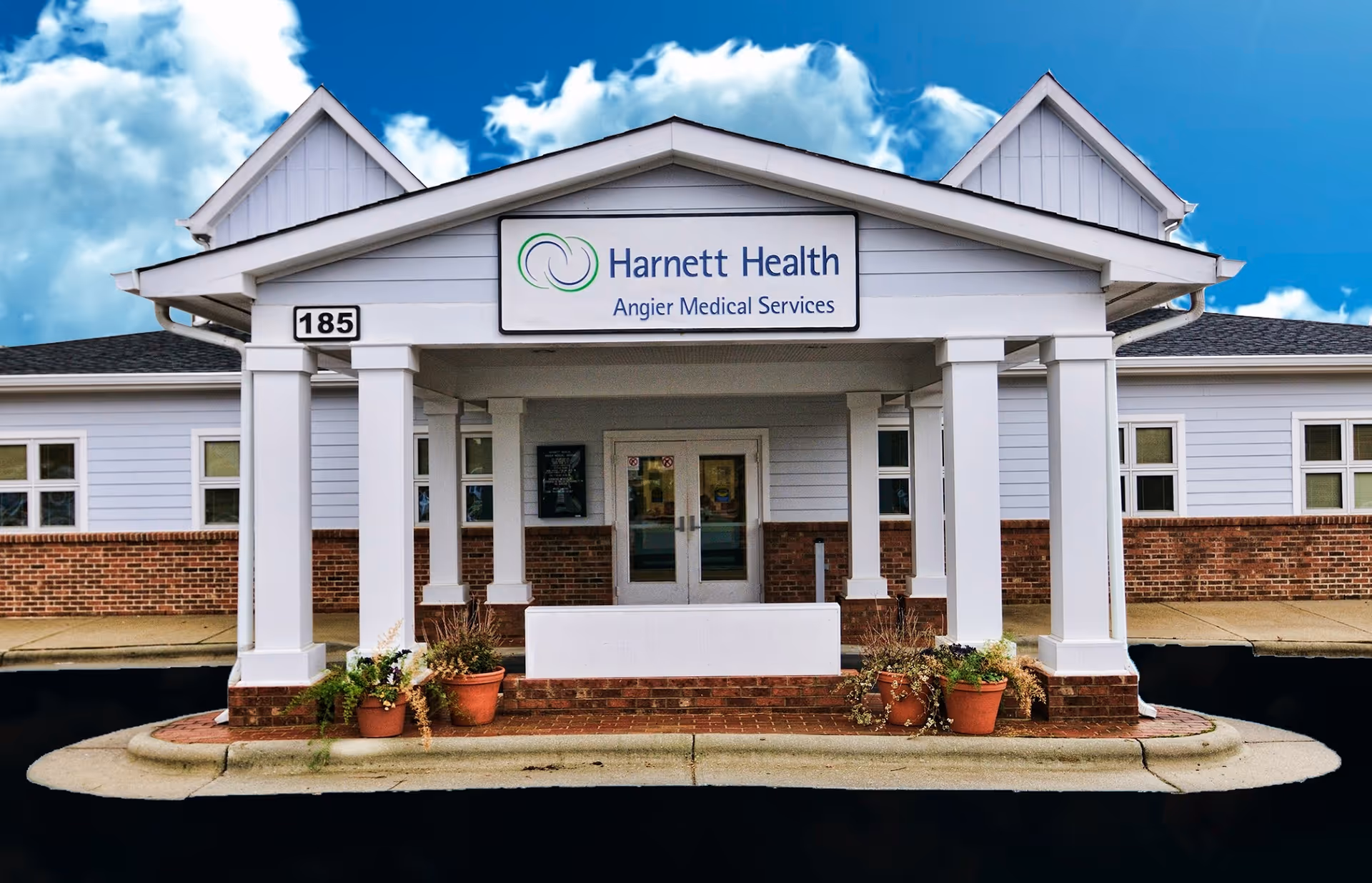 Front view of Angier Medical Services building with white siding, brick base, and columns.