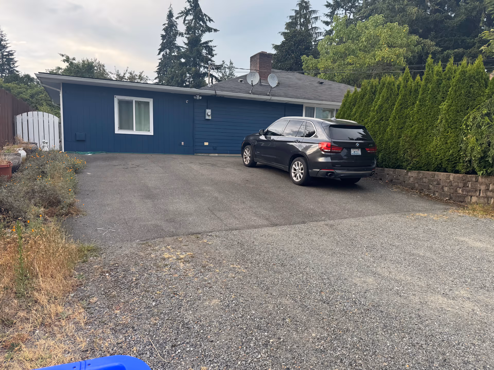 Blue single-story building with a long driveway and a dark SUV parked near the entrance