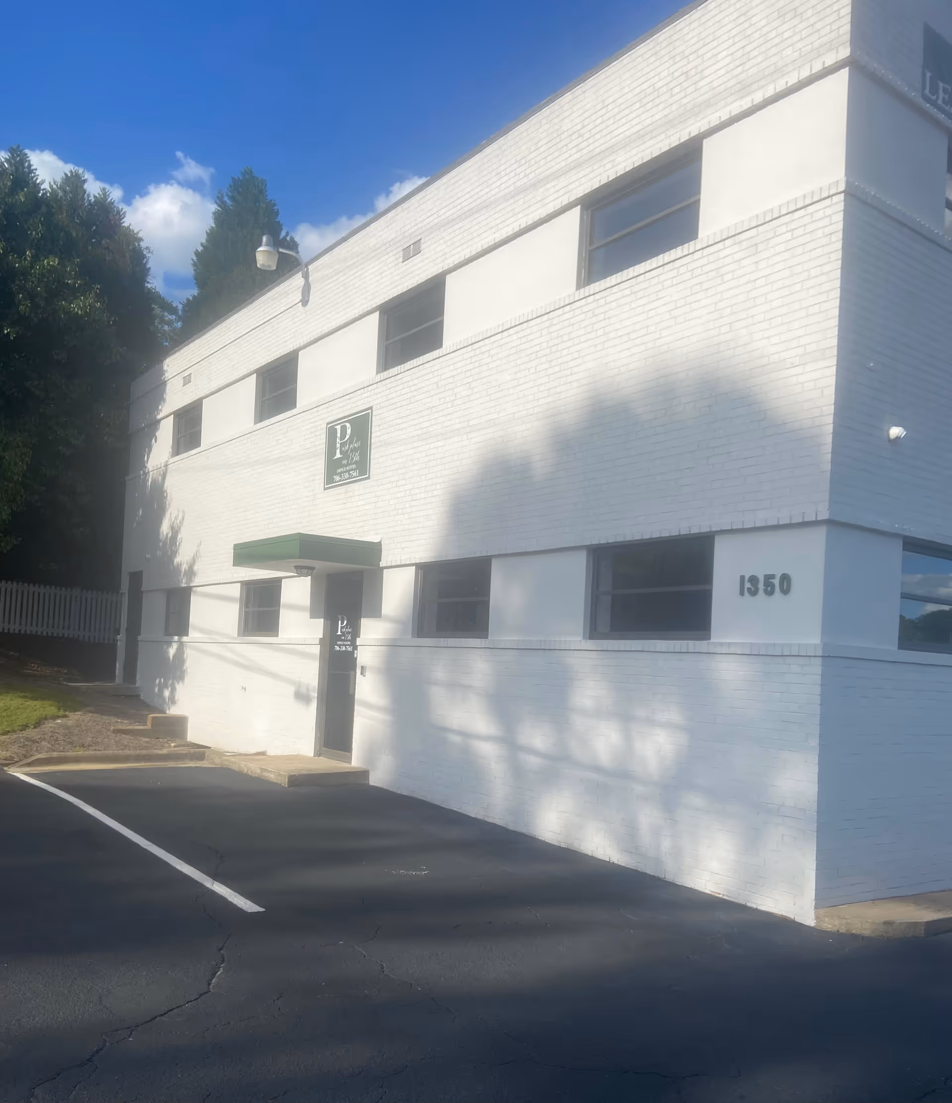 Two-story white brick senior living building with a green awning and parking lot