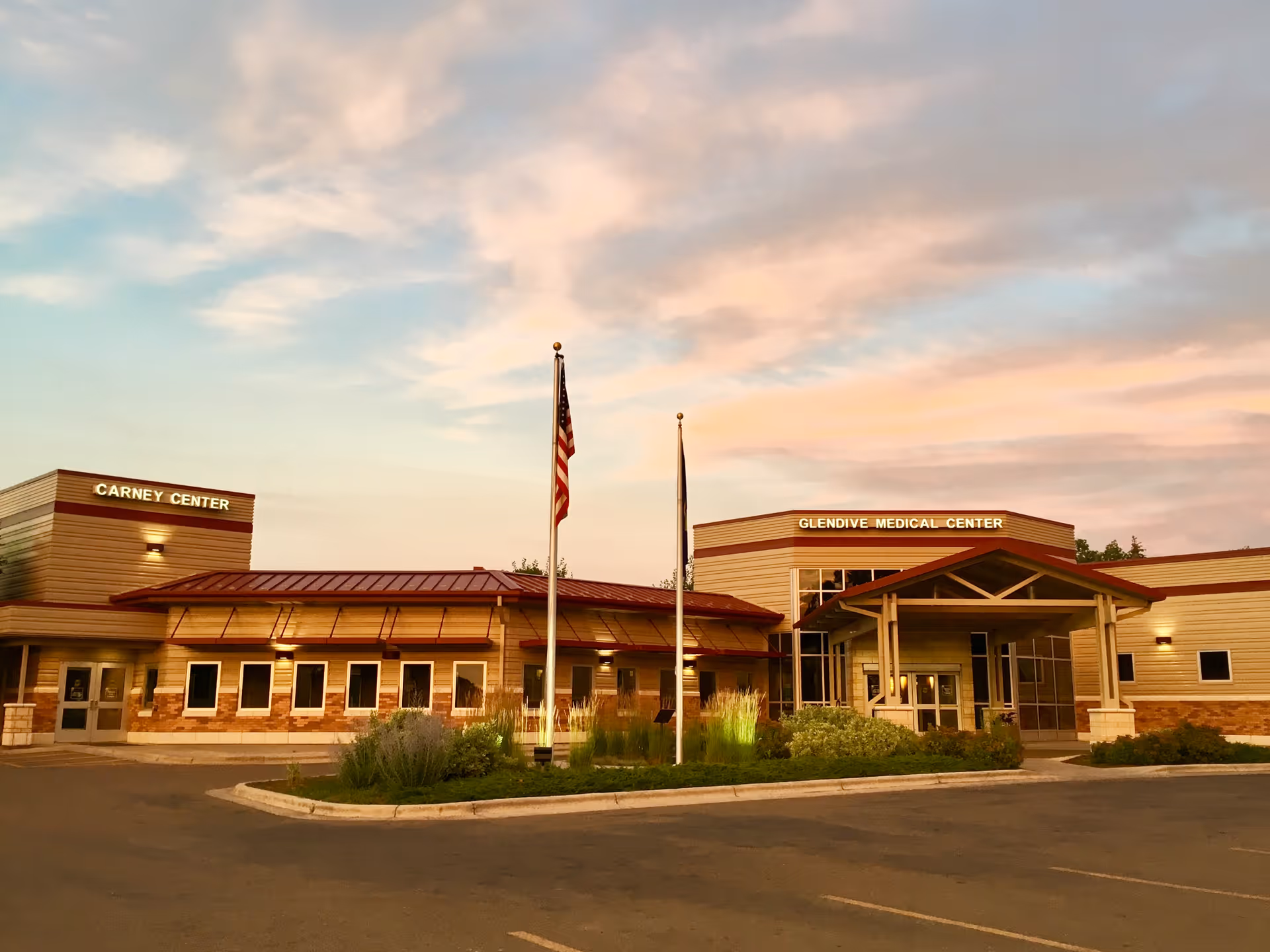 Sunset-lit exterior of Glendive Medical Center with flagpoles and entrance.