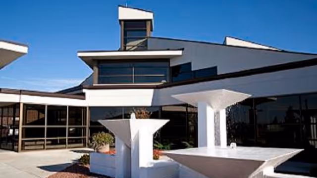 Modern building entrance with large glass windows and white geometric planters outside.
