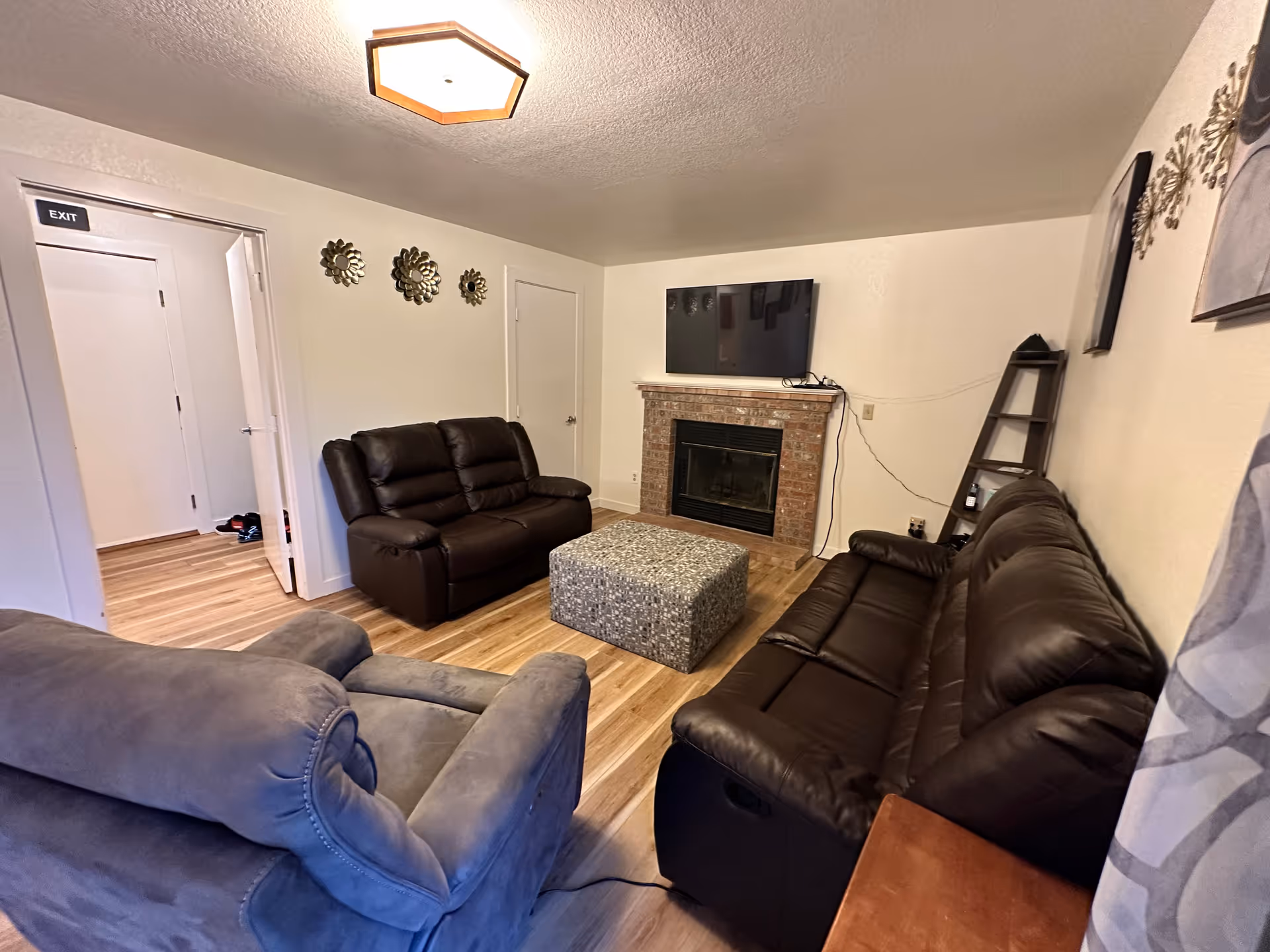 Cozy living room with leather sofas, fireplace, mounted TV, and decorative wall art.