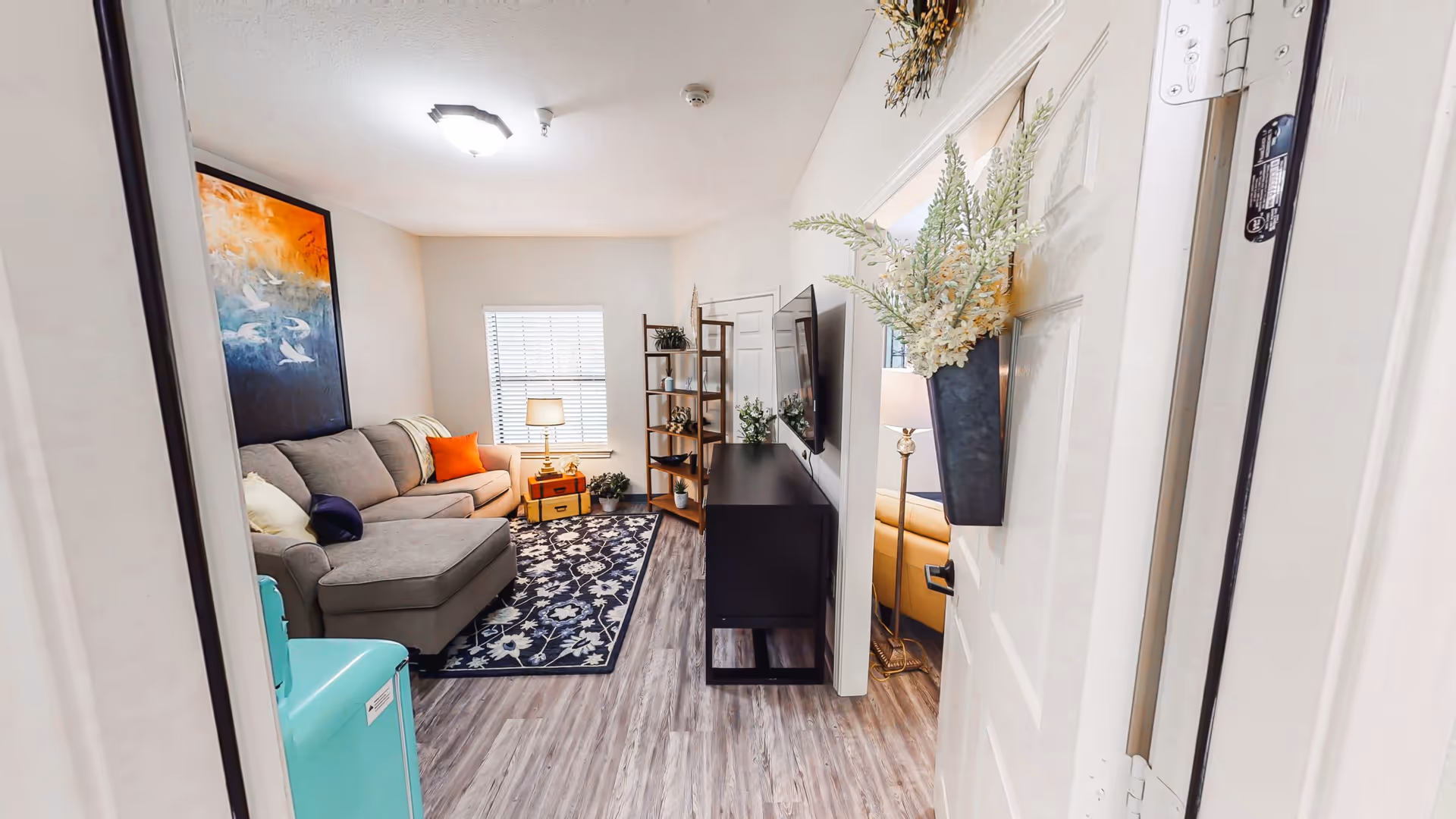 Cozy living room in a senior care home with sofa, rug, and TV.